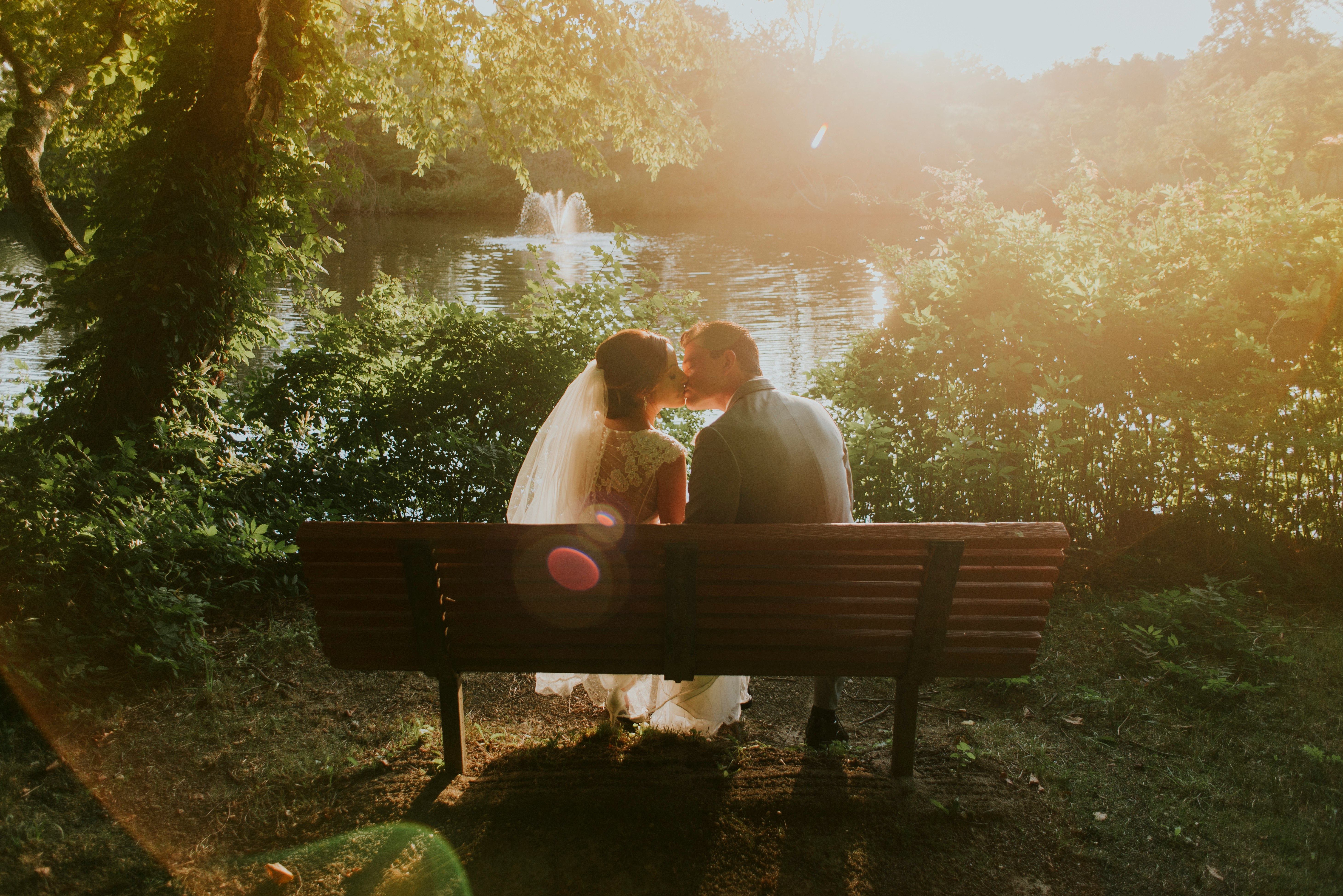 newlywed sitting on bench white kissing